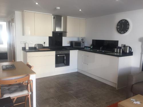 a kitchen with white cabinets and a table and a clock at Cloverlea Cottages in Bristol