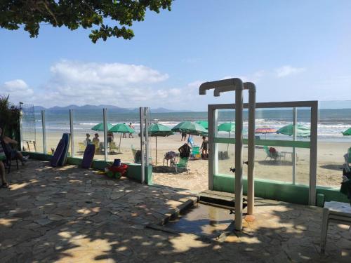a beach with green umbrellas and people on the beach at Pousada Vila Verde in Porto Belo