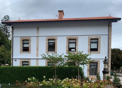 a white house with a hedge in front of it at Apartamentos La Bicicleta in Puente Viesgo