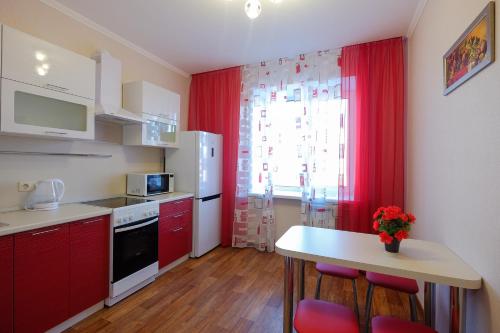 una cocina con armarios rojos y una mesa con sillas. en ОК! Советская, 60 №1, en Tomsk