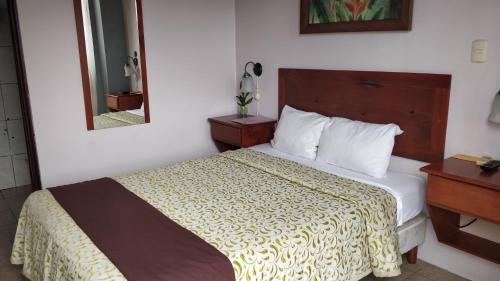 a hotel room with a bed and a mirror at Hotel Las Colinas in Fortuna