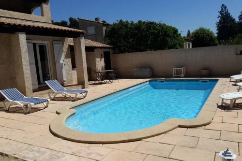 une piscine avec deux chaises à côté d'une maison dans l'établissement jolie villa avec piscine, à Marignane