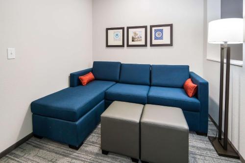 a living room with a blue couch and an ottoman at Comfort Suites DeSoto Dallas South in DeSoto