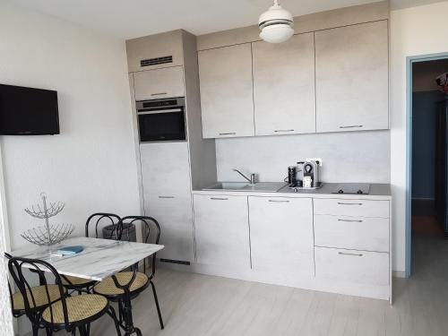 une cuisine avec des armoires blanches et une table avec des chaises dans l'établissement Residence Beaupre, à Canet