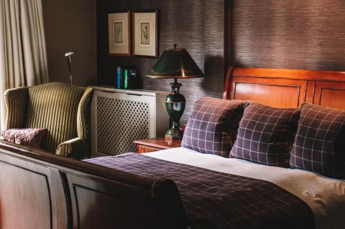 a bedroom with a bed and a lamp and a chair at Langshott Manor - Luxury Hotel Gatwick in Horley
