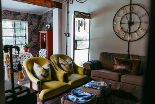 a living room with a couch and chairs and a clock at Timeless Bloemfontein in Bloemfontein