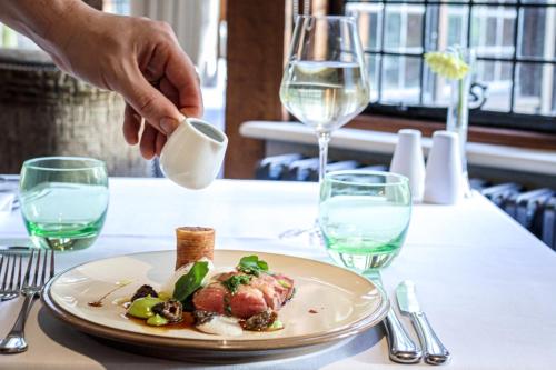 a person is pouring a glass of milk over a plate of food at Langshott Manor - Luxury Hotel Gatwick in Horley