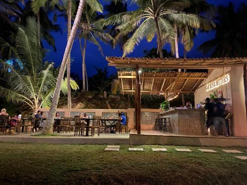 a restaurant with tables and palm trees at night at Singhe House in Dickwella