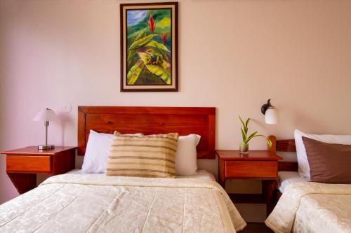 a bedroom with two beds and a painting on the wall at Hotel Las Colinas in Fortuna