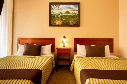 a hotel room with two beds and a picture on the wall at Hotel Las Colinas in Fortuna