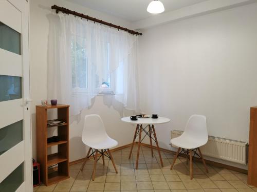 a room with a table and three white chairs at WHITE Apartment in Jabłonna