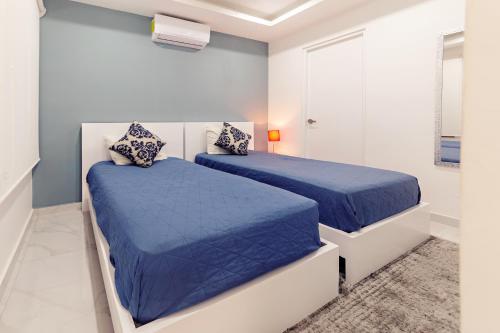 Duas camas num quarto branco com lençóis azuis em Mararena Condos by Nah Hotels em Playa del Carmen