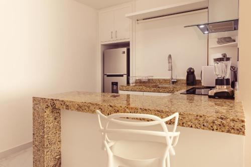 a kitchen with a white chair sitting at a counter at Mararena Condos by Nah Hotels in Playa del Carmen