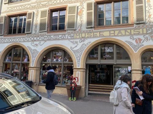 a building with people standing in front of a store at LE MUSCAT in Colmar