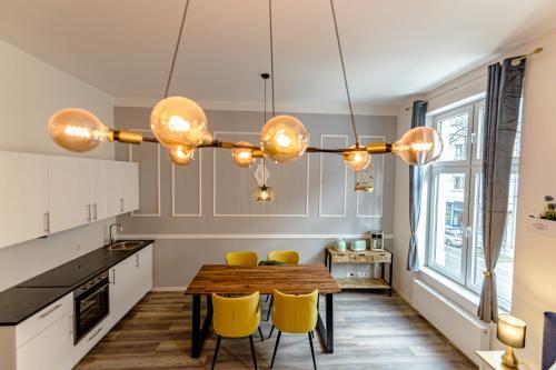 Downtown Apartments Bilk في دوسلدورف: مطبخ بطاولة خشبية وكراسي صفراء