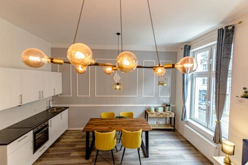a kitchen with a wooden table and yellow chairs at Downtown Apartments Bilk in Düsseldorf