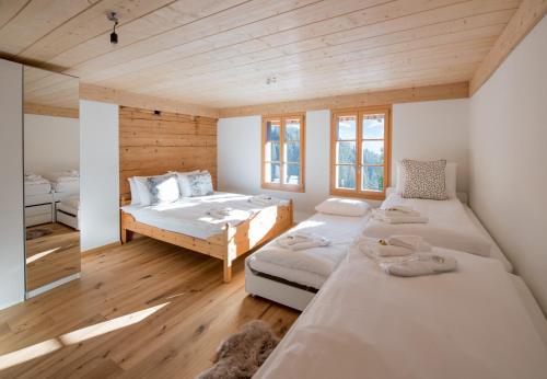 two beds in a room with wooden floors and windows at Chalet Ledibach in Wengen