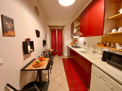 ローマにあるB&B Stelle Di Romaの赤いキャビネットとテーブル付きのキッチンが備わります。