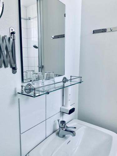 a white bathroom with a sink and a mirror at Drottning Victorias Hotell & Vilohem in Borgholm