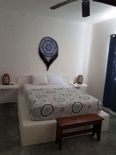 a white bed with a white comforter and a clock on it at Loto Tulum in Tulum