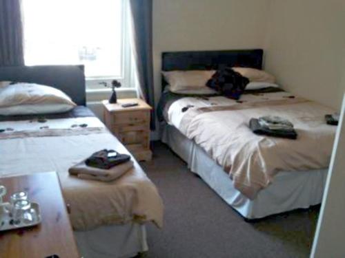 1 dormitorio con 2 camas, mesa y ventana en Clifton Hotel, en Weymouth