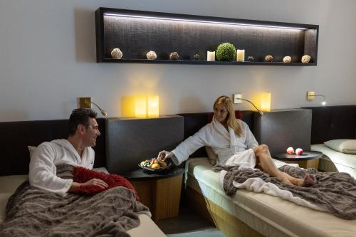 a man and woman sitting on beds in a hotel room at Dominik Alpine City Wellness Hotel - Adults only in Bressanone