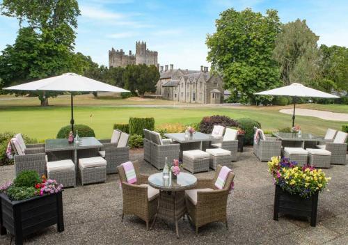 a patio with tables and chairs with a castle in the background at The Lodges at Kilkea Castle in Kilkea