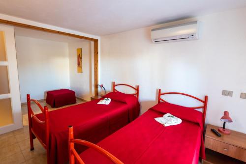 ポッツァッロにあるAl tegolaioの赤いシーツが備わるドミトリールームのベッド2台