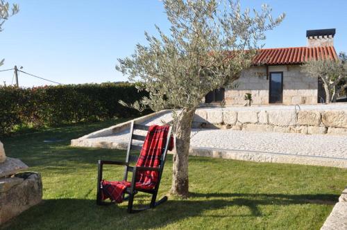 a red chair sitting next to a tree at Quinta do Olival in Vilas Boas