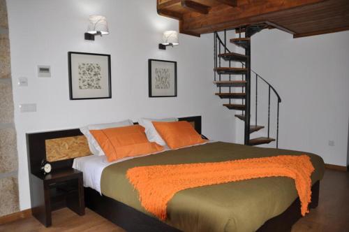 a bedroom with a bed with orange pillows and a staircase at Quinta do Olival in Vilas Boas