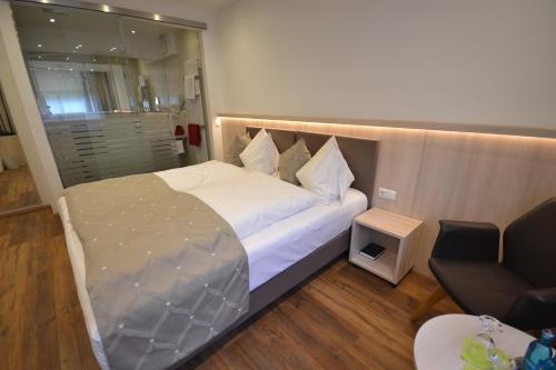 a bedroom with a large bed and a chair at Hotel-Gasthof Weisses Ross in Schwaig bei Nürnberg