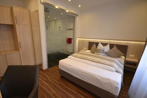 a bedroom with a bed and a chair and a window at Hotel-Gasthof Weisses Ross in Schwaig bei Nürnberg