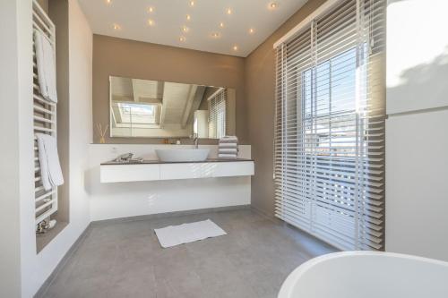een badkamer met een wastafel, een toilet en een spiegel bij Apartment Walserblick in Oberstdorf