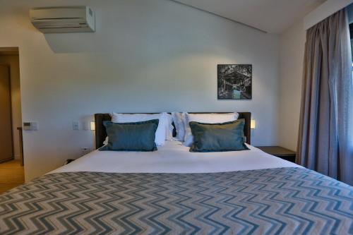 a bedroom with a large bed with blue pillows at Quality Hotel Blumenau in Blumenau