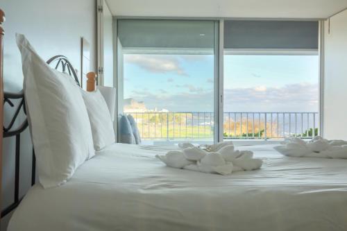 uma cama branca com almofadas brancas e uma janela grande em Quinta do Mar em Angra do Heroísmo