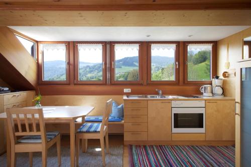 a kitchen with a table and chairs and some windows at Bio Ferienbauernhof Greber in Schwarzenberg im Bregenzerwald