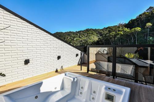a white bath tub on a balcony with a bedroom at Quality Hotel Blumenau in Blumenau