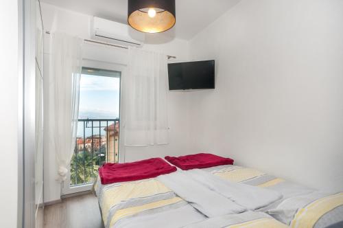 a bed in a room with a window and a television at Apartments Patricija in Opatija