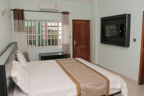 a bedroom with a bed and a flat screen tv at BERACA INN in Cotonou
