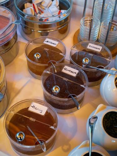 a table topped with containers of honey and utensils at Hotel Landhaus in Gstaad
