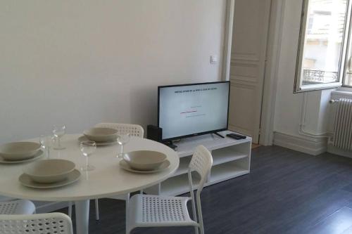 une salle à manger blanche avec une table et une télévision dans l'établissement F3 lumineux & cosy au centre de Mulhouse, à Mulhouse