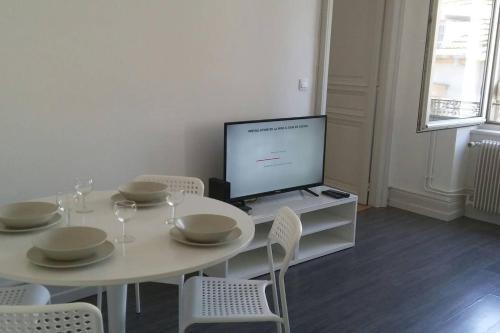 biała jadalnia ze stołem i telewizorem w obiekcie F3 lumineux & cosy au centre de Mulhouse w Miluzie