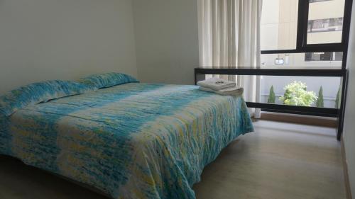 - une chambre avec un lit doté d'une couette bleue et d'une fenêtre dans l'établissement 1410 Habitación en Lujoso Departamento - Atelier, à Quito