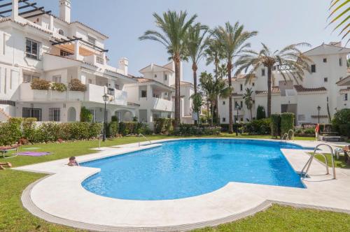 a swimming pool in front of a building at AB Properties - Chic Duplex Penthouse -3mn to Puerto Banus and Beach- Golden Mile- Los Naranjos- Mountain View -Pool and Tropical Garden in Marbella