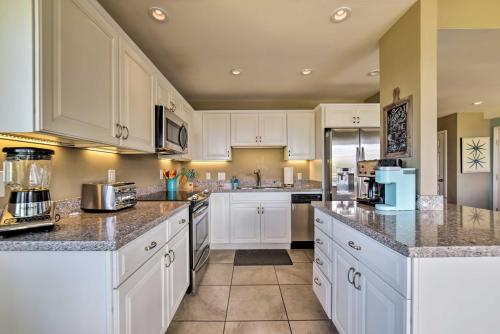 a kitchen with white cabinets and granite counter tops at Ocean-View Kihei Condo with Pool Access! in Kihei