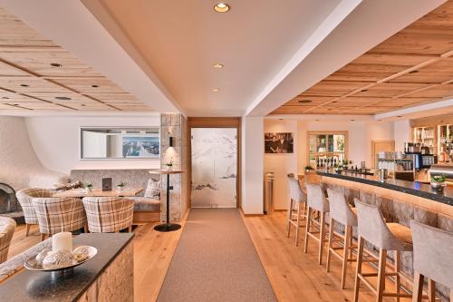 a kitchen and living room with a bar and chairs at Hotel Enzian in Zürs am Arlberg