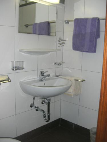 a bathroom with a sink and a mirror and purple towels at Pension Garni Gerhard in Oetz