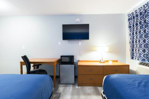 a hotel room with two beds and a desk and a tv at Americas Best Value Inn East Peoria in Peoria