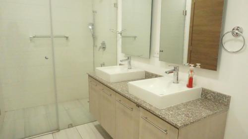 La salle de bains est pourvue de 2 lavabos et d'une douche. dans l'établissement 1410 Habitación en Lujoso Departamento - Atelier, à Quito