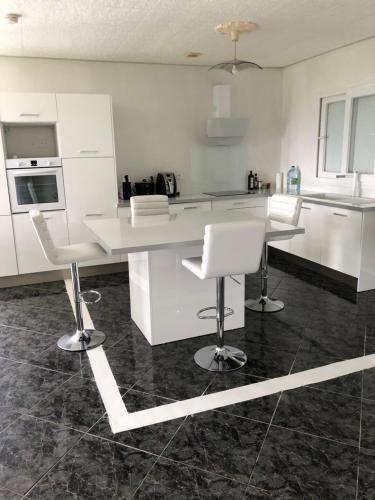 a kitchen with a white counter and white chairs at Cool Home in Sainte-Marie